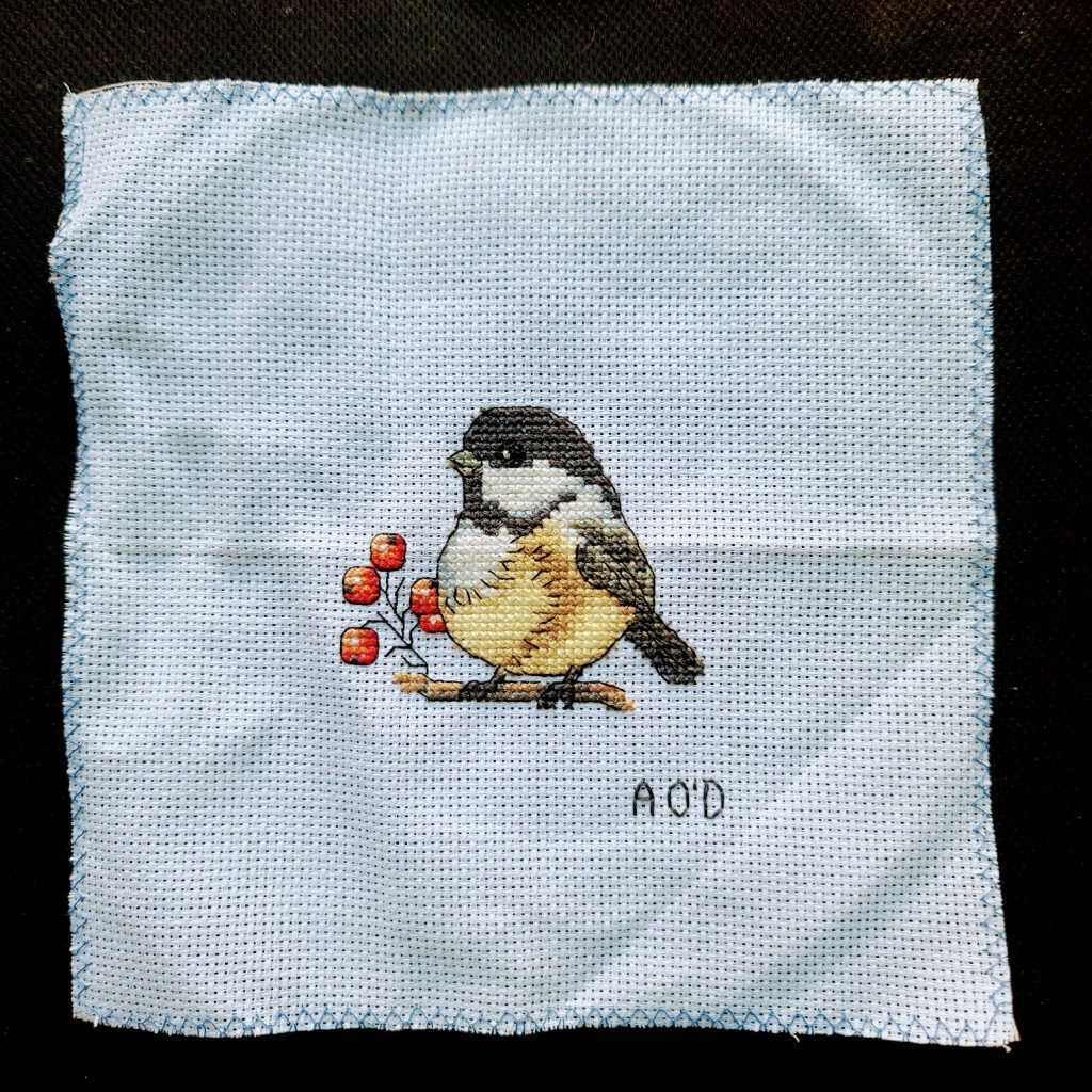  Cross-stitch of a small bird with some berries.  Chickadee.
